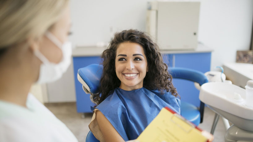 woman sit on the dental chair and smiling and lady dentist filling out forms